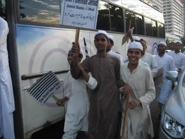 In this picture we can see some people are walking along with vehicles on the road and they are...