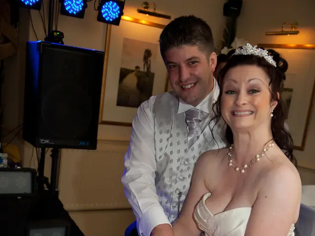 There is a man and woman holding a knife. In front of them there is a table. On that there is a...