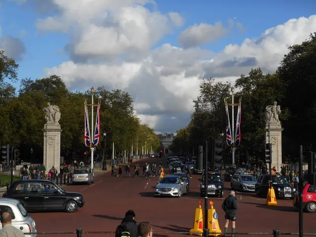 In this image on the road few cars are moving, there are few people walking on the road. This is a...