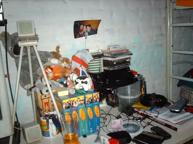 In the image there are books,remote,earphones,cash,cups,tripod,photography,toys on a table, in...