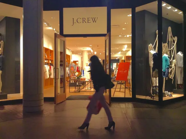 In the picture there is a shopping complex present, there are glass walls and doors present, inside...