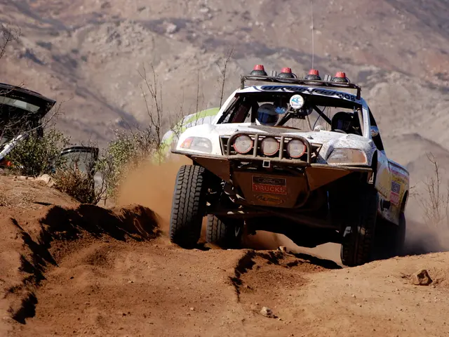 In the middle a car is moving, which is in white color and in the left side there are green plants.
