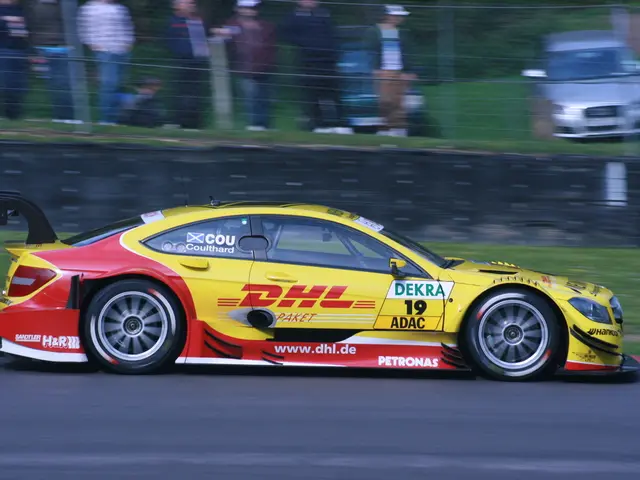 In this image we can see a racing car on the road, in the background there are few people standing...