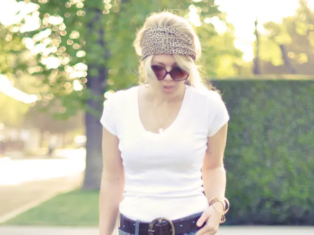 A woman is walking holding bag, there are trees, these is grass.