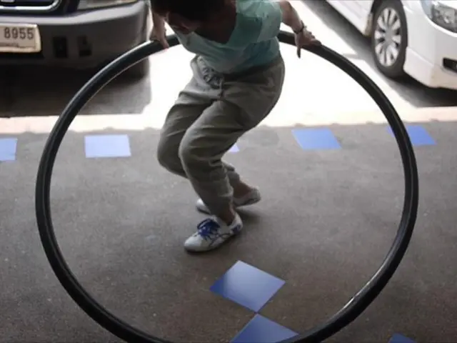 In this image we can see there is a person holding an exercise wheel. And there are cars on the...