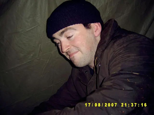 In this image we can see a person wearing jacket, skull cap, beside him there is a sheet.