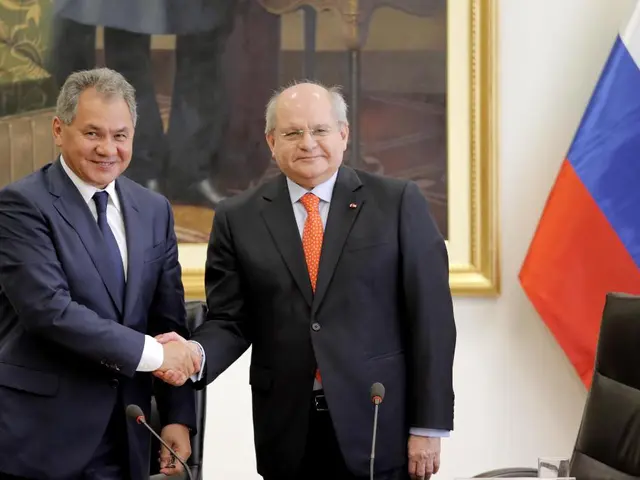 In this picture, there are two men wearing blazers. Both of them are shaking hands. Before the,...