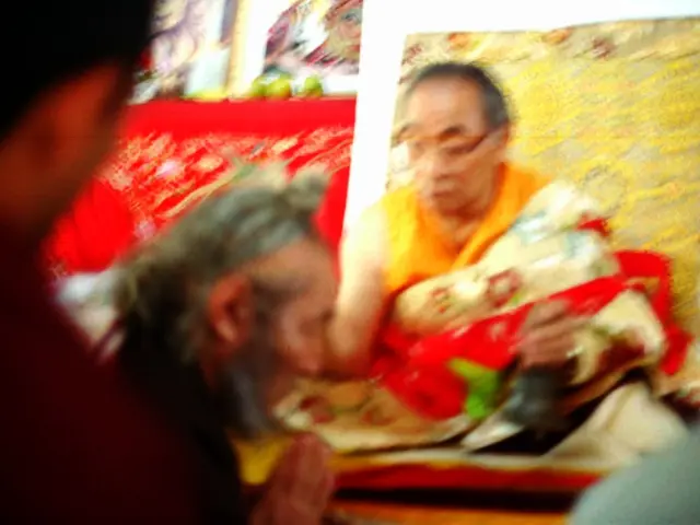 In this image, I can see a buddhist including two people behind this three people, I can see few...