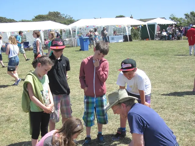 There are two people kneeling on the ground and doing some work, there are children in the...