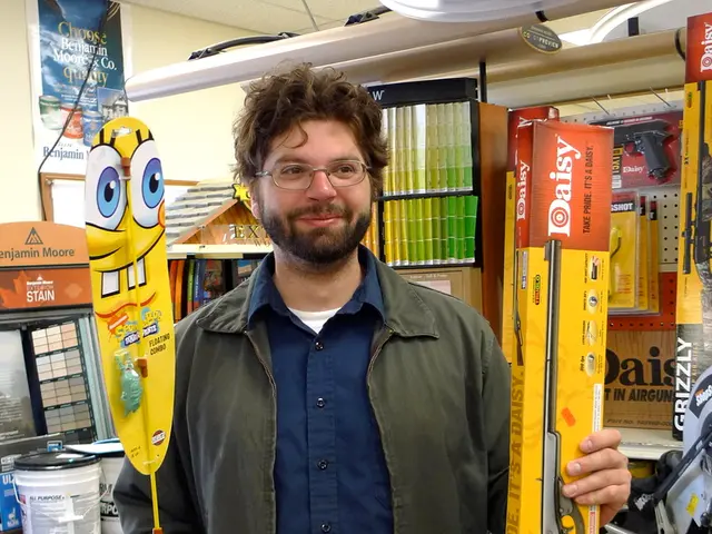 There is a person wearing a specs. He is holding a box and some other thing in the hands. On the...