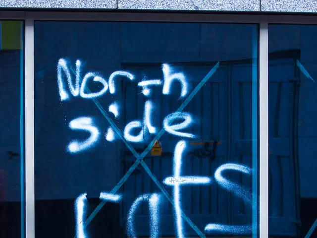 In this image we can see some text on the window and a barrier pole on the road.