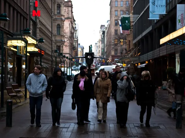 In this image in the center there are persons walking. In the background there are empty chairs,...