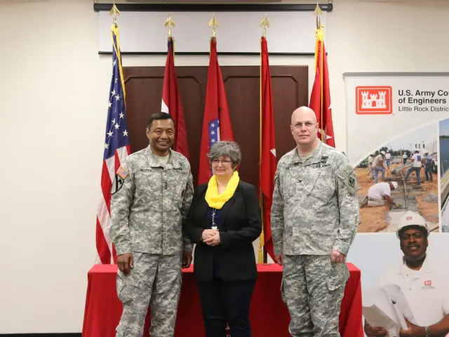 In this image two persons wearing uniform. In between there is lady wearing black suit. In the...