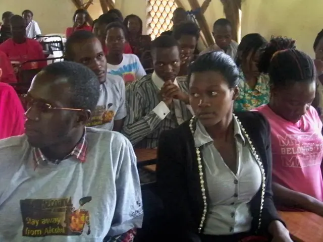 As we can see in the image there is a wall and few people sitting here and there on benches.