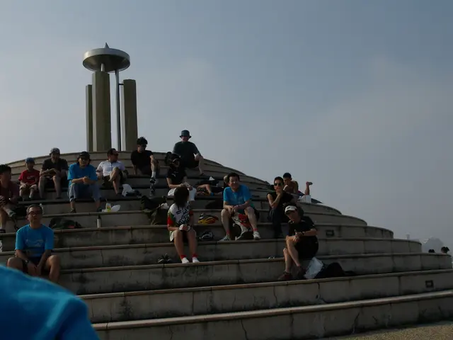 This is the picture of a place where we have some people sitting on the staircase and behind there...