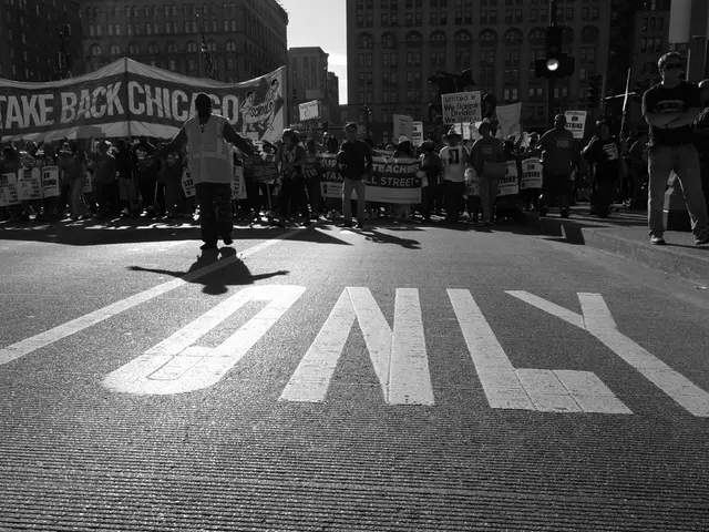 This is a black and white pic. There is a text written on the road. We can see few people are...