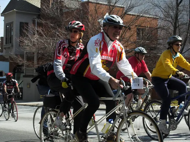 This picture is clicked outside the city. Here, we see five people riding bicycle. Behind them, we...