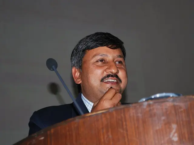 In this picture we can see a person standing and smiling. There is a podium and a mic.