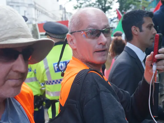 In this image in the foreground, we can see many people standing, and a person on the left side...