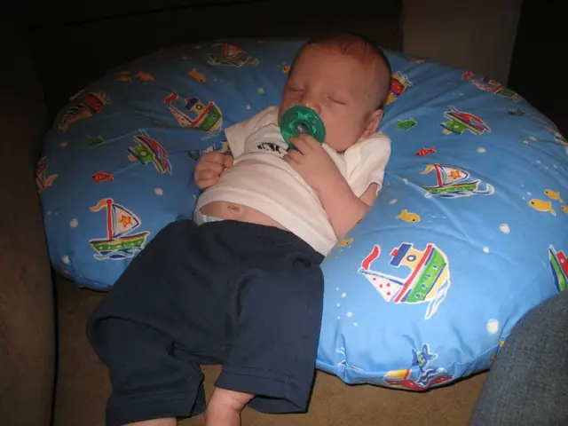 In this image there is a kid sleeping, there is a nipple in the mouth of the kid, there is a cough...