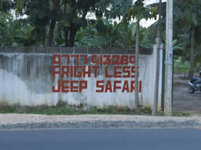 In this image there is a text written on the compound wall, behind the compound wall there are...