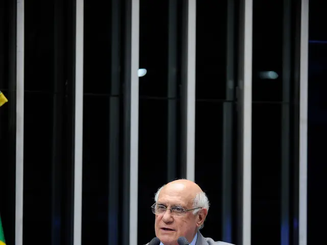 In this image in the center there is one person who is is talking, in front of him there are mikes...