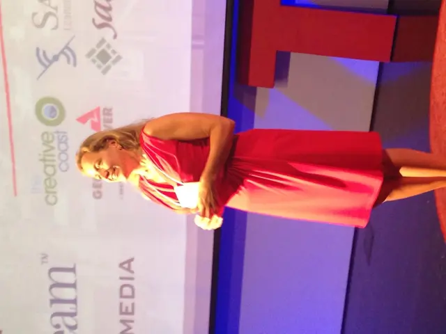 On the right side, there is a woman in a pink color dress, holding a document, smiling and standing...