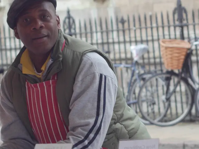 In this image there is a person wearing a cap. Behind him there are few bicycles on the pavement....