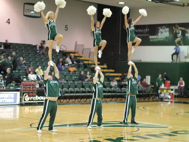 In this image we can see women and men performing gymnastics and women are holding pom poms in...