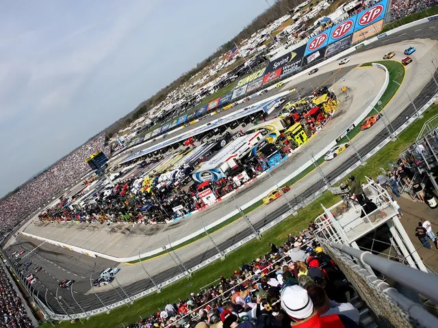 In this image, we can see a crowd. There is a racing track and some cars in the middle of the...