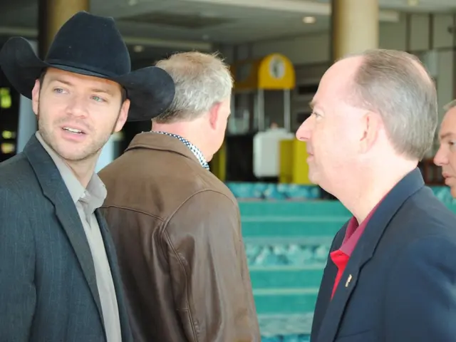 In the image we can see there are people standing and in front there is a man wearing suit and hat,...