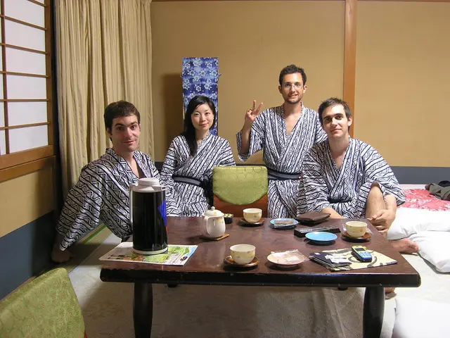 A window with curtain. These persons are sitting on a chair. On this table there is a tea pot, cup,...