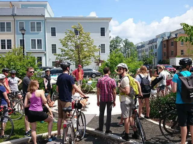 This picture shows a group of people holding bicycles in their hand and we see people standing and...