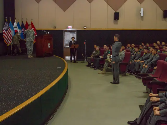 In this picture we can see some people are sitting on chairs and four persons are standing, on the...