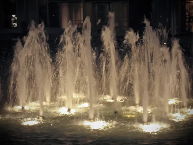 In the foreground there is a fountain. At the back there is a building. At the bottom there is...