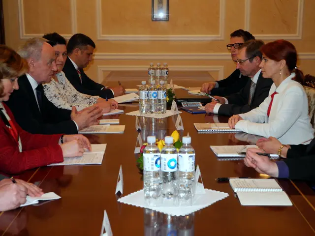 In this image there are nine members sitting in conference hall. There is a table,on the table...