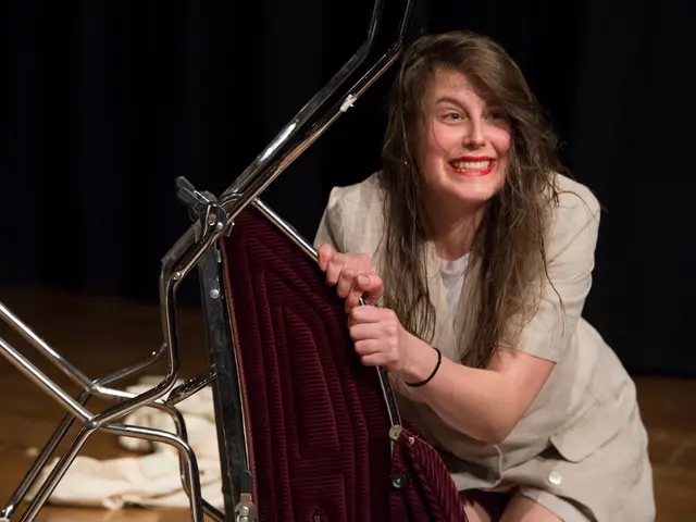 One lady is sitting on a chair and smiling. And she is holding the chair. She is wearing an ivory...