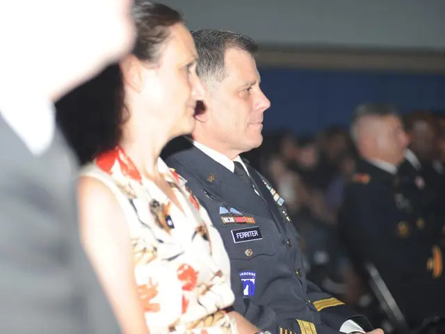 In this image we can see a woman wearing dress and a man wearing uniform are sitting here. The...