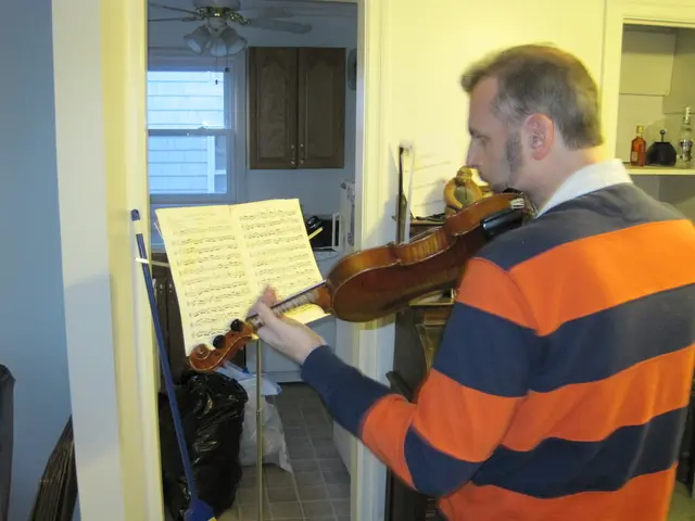 The picture is taken in a closed room where one person is playing violin in front of him there is...