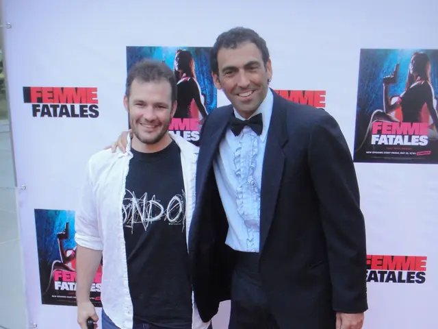 In this image there are two people standing with a smile on their face are posing for the camera,...