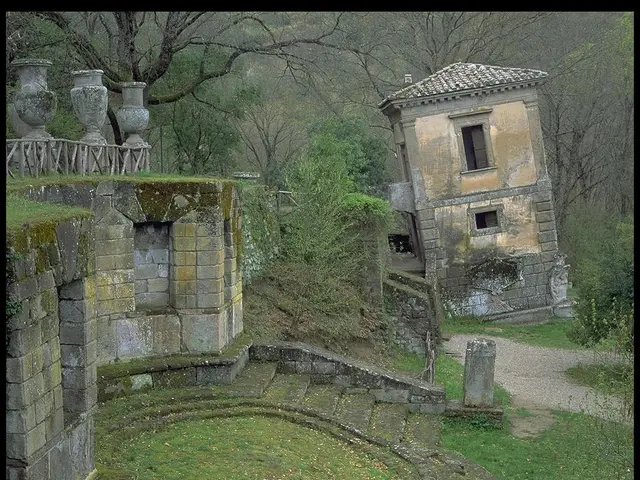 In this image I can see the ground, some grass on the ground, few stairs, few buildings, the...