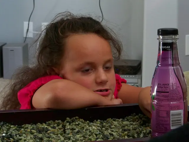 In this image there is a kid wearing red color dress touching a bottle.