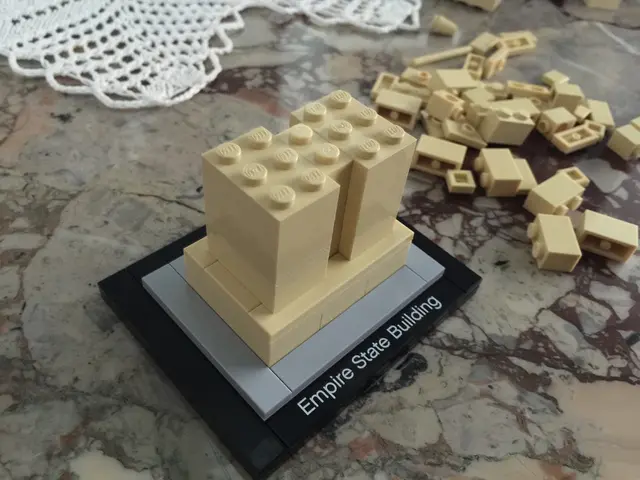 In the foreground of this picture, there is a building block bricks arranged on the surface. In the...