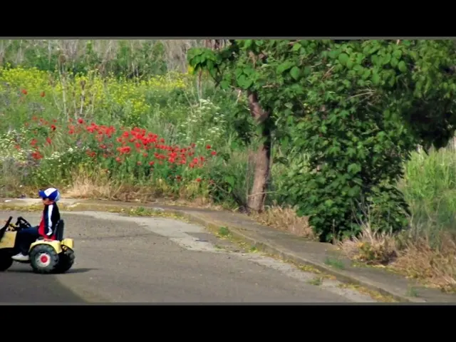 In this image in the center there is a toy vehicle and there is a kid sitting in the vehicle. In...