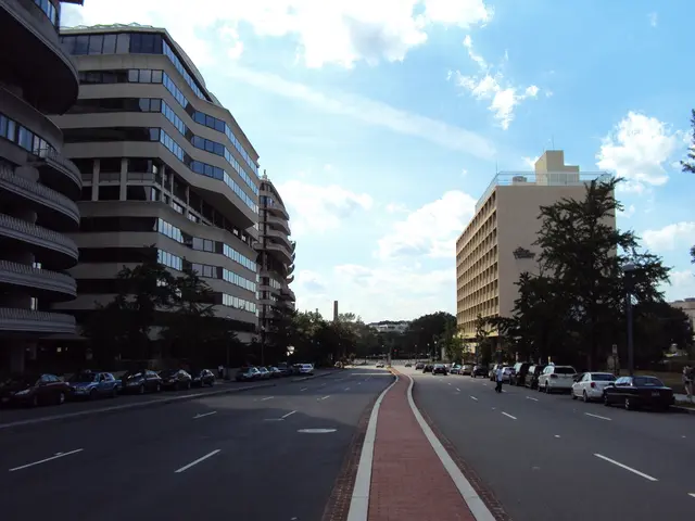 In the image I can see a place where we have some buildings, trees and some cars parked on the...