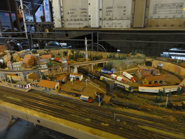 In this image there is a miniature on the table. Bottom of the image there is a rail track. Beside...