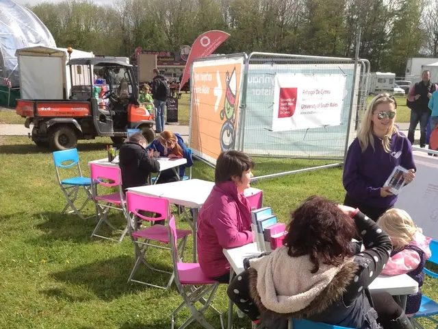This image is clicked outside. There are so many tables and chairs ,people are sitting in chairs,...