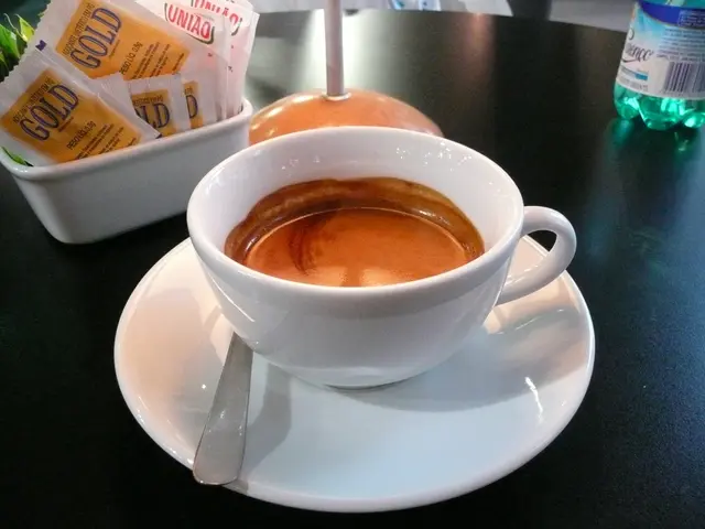 there a cup , saucer, spoon on the table and water bottle, bowl of sachets.