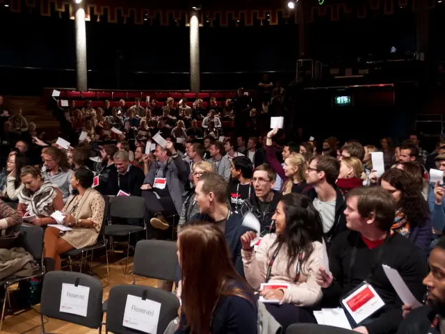 In this image there are group of people sitting in chairs by holding a papers in their hand by...
