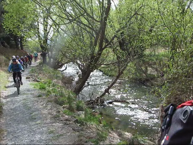 On the left side a group of people are riding the cycles, in the middle water is flowing and there...